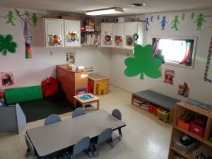 Classroom with small tables and chairs, storage, and wall decorations