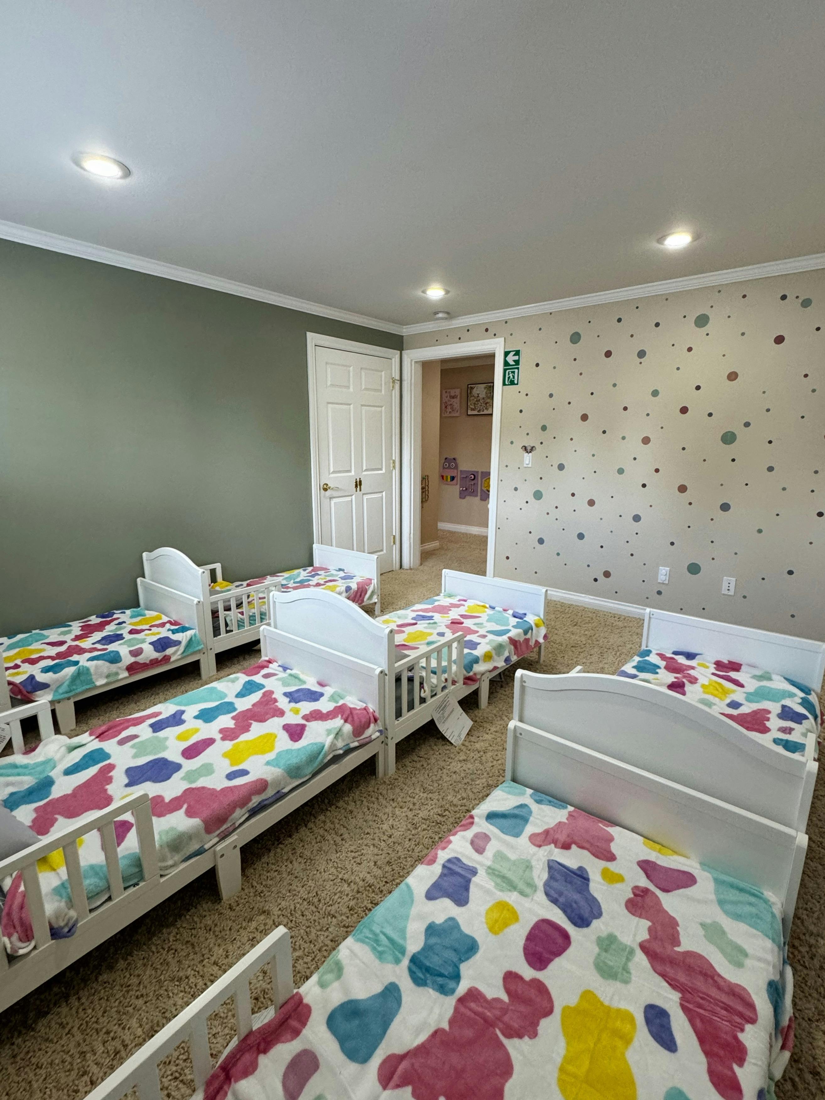 Multiple small beds with colorful blankets in a room