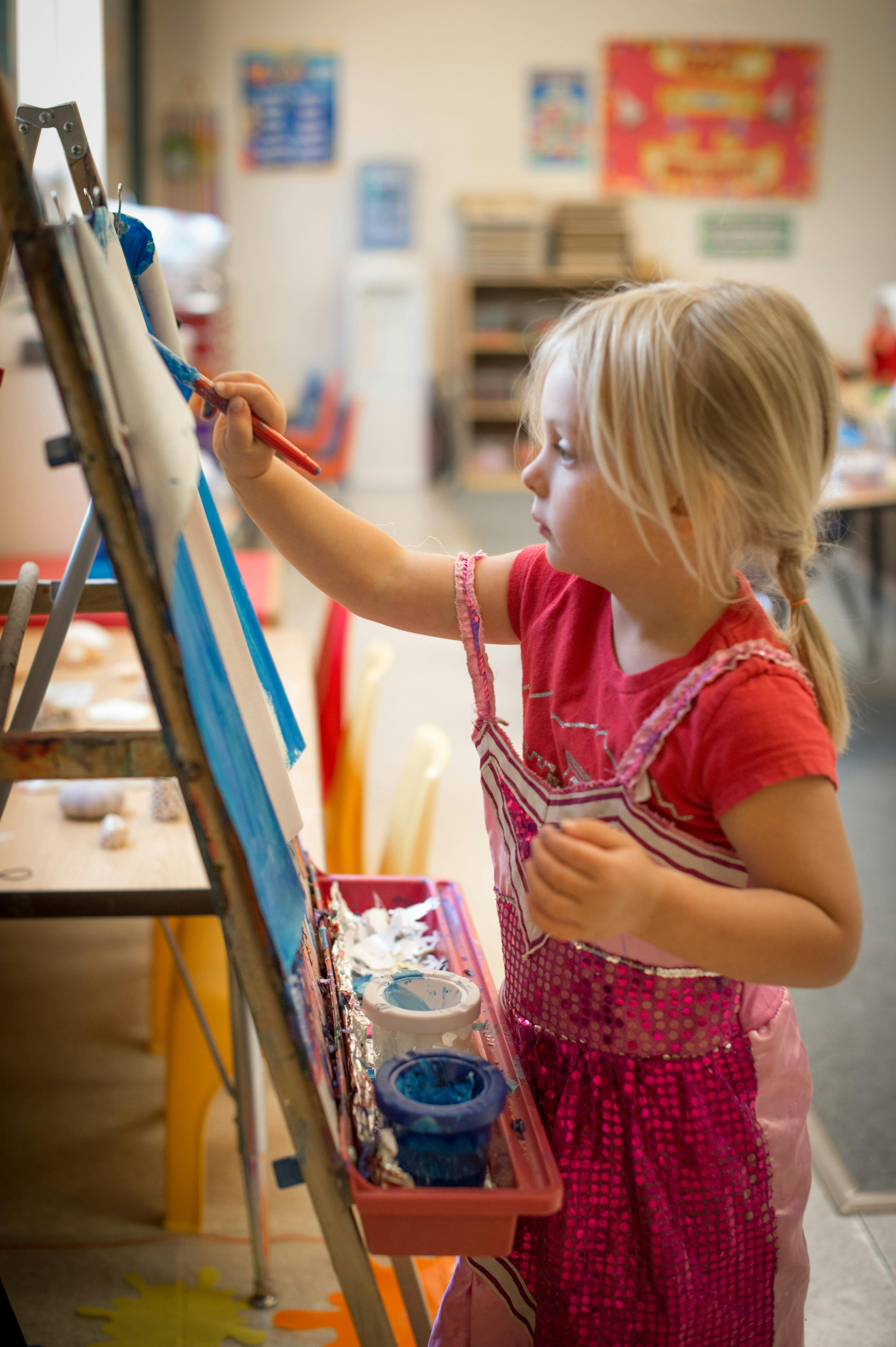 child painting on an easel in a classroom