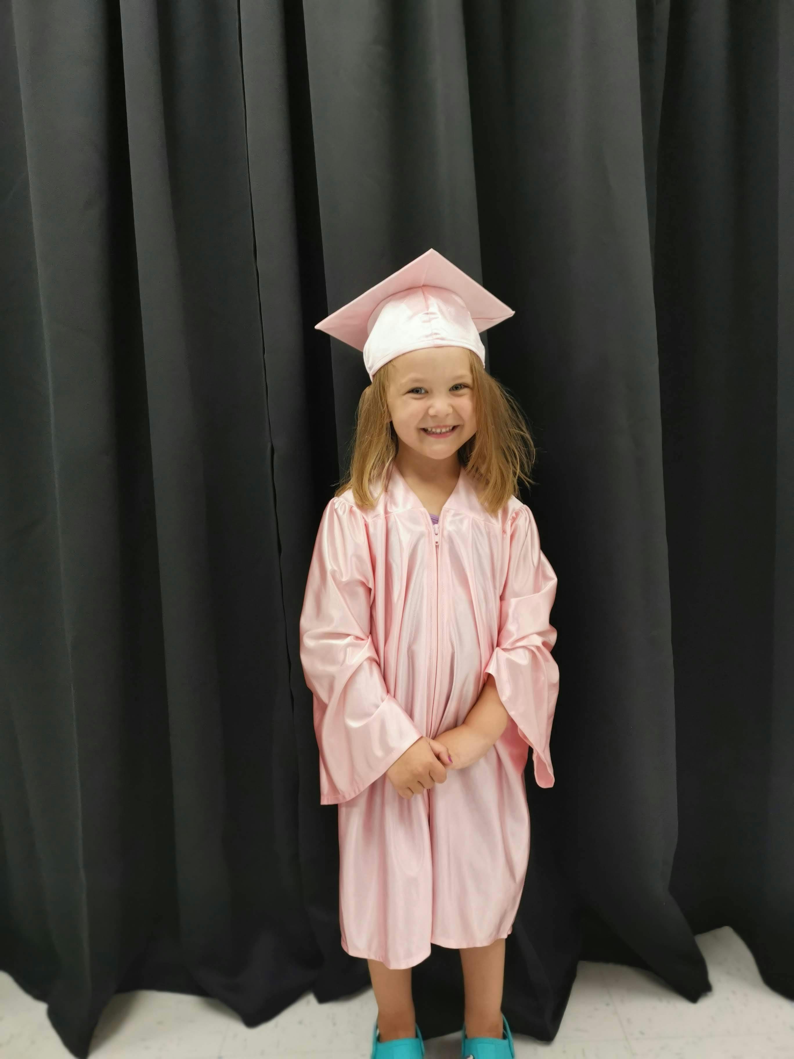 Child in a pink graduation cap and gown