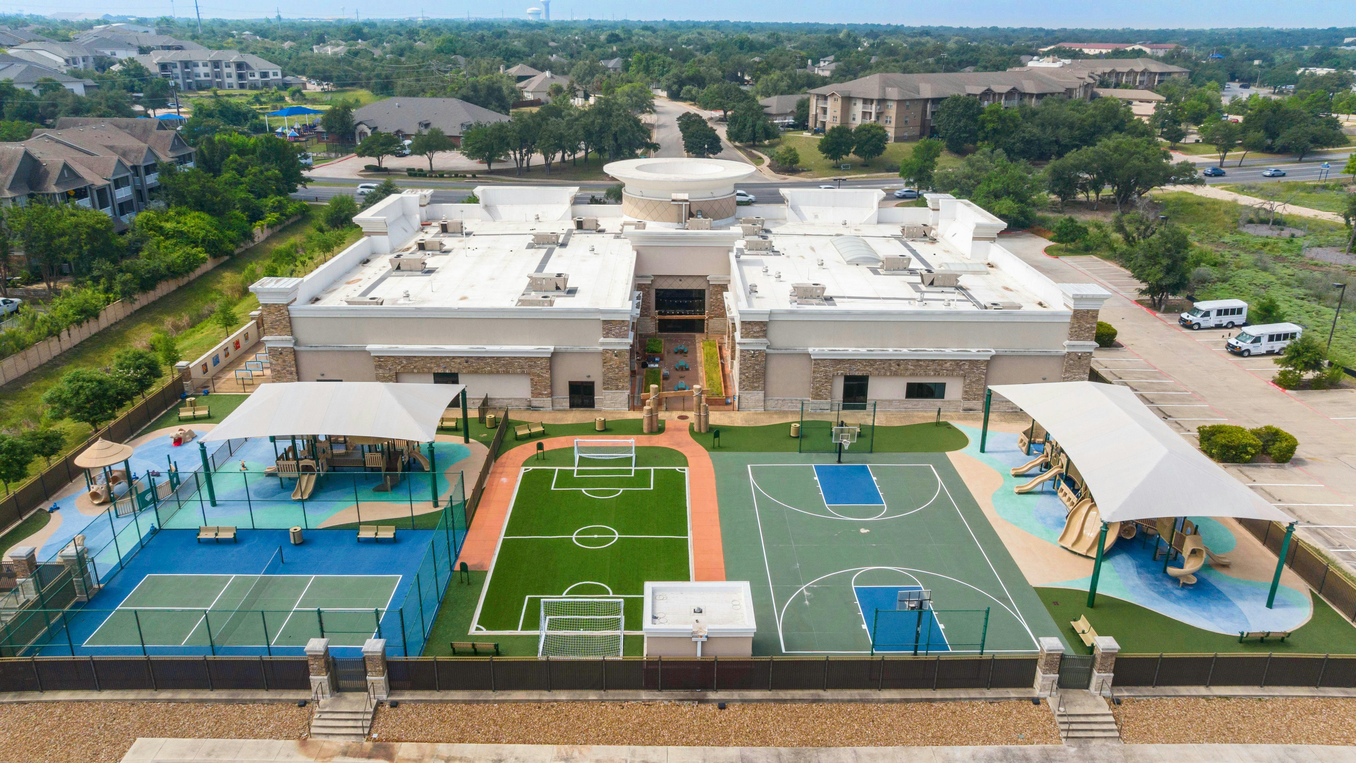 Aerial view of a building with multiple sports courts and playgrounds