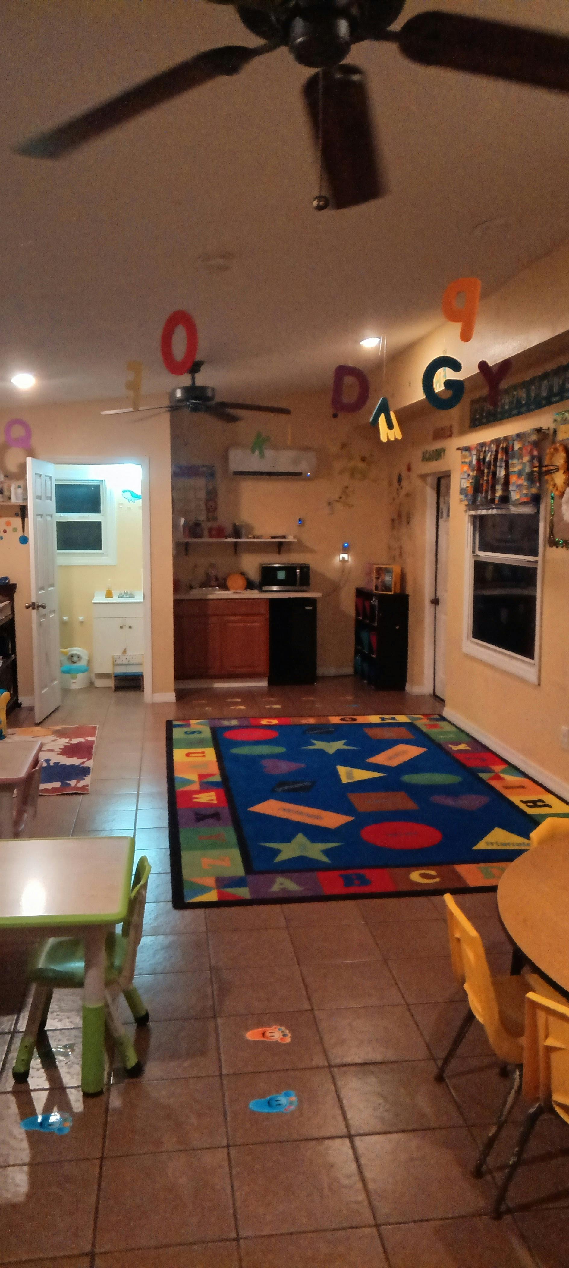 Classroom with a colorful rug, tables and chairs, and floating letters