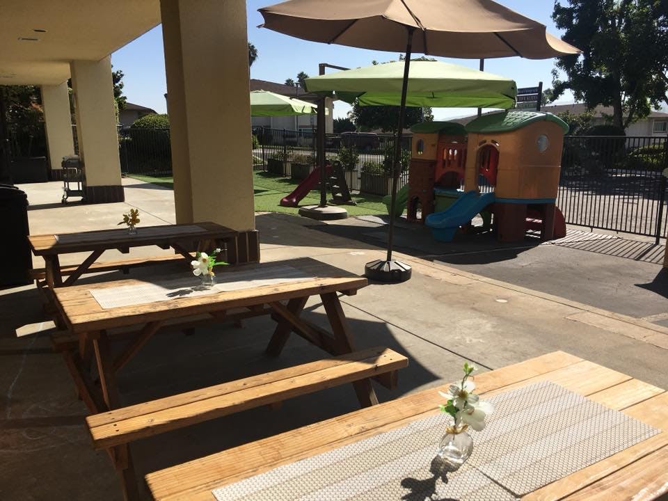 Picnic tables on a patio with a playground in the background