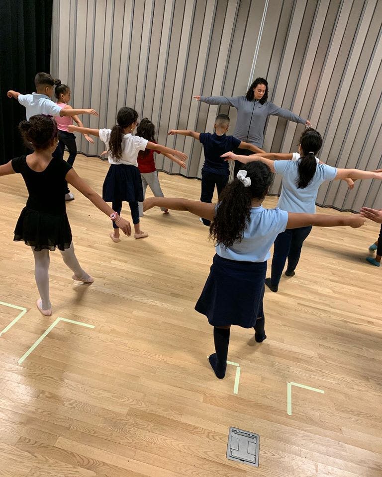 Adult and children in a room with arms outstretched
