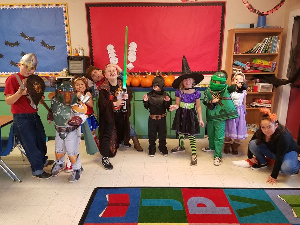Children and adults in Halloween costumes in a classroom