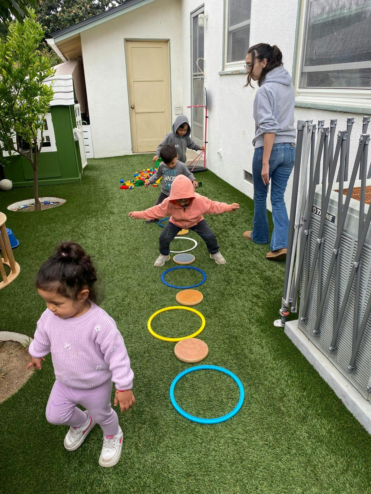 People and children playing on an outdoor turf with rings and pads