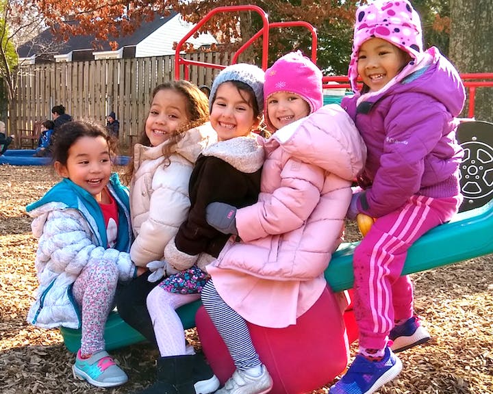 Four children sitting on a playground seesaw