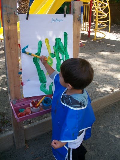 Child painting on an easel outdoors