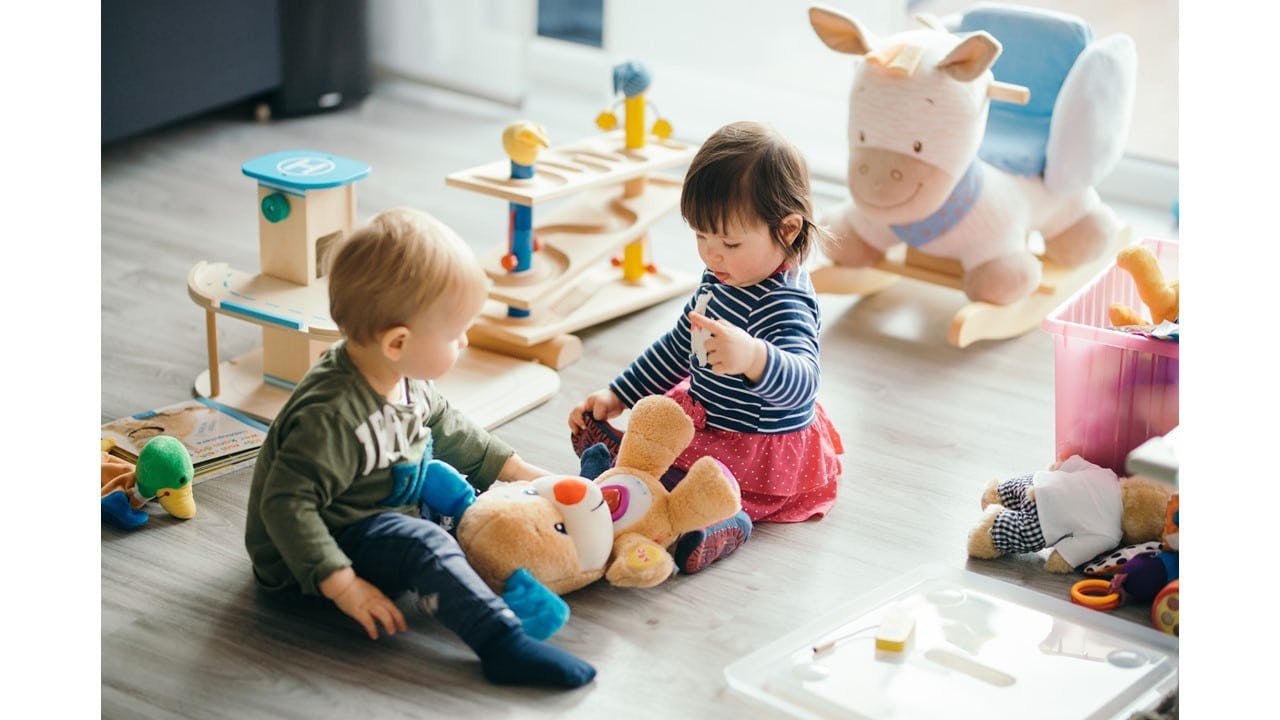 Two children sitting on the floor playing with toys