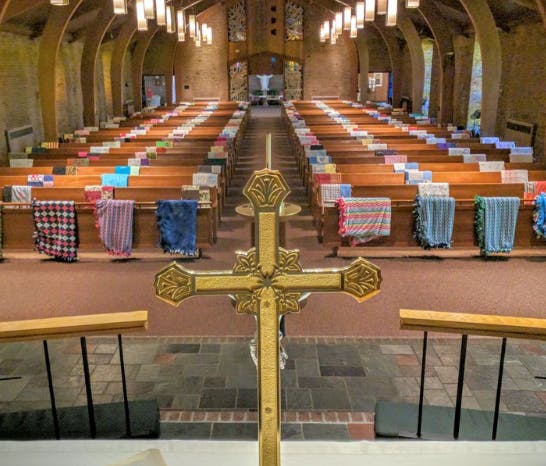 Golden cross in front of church pews with blankets