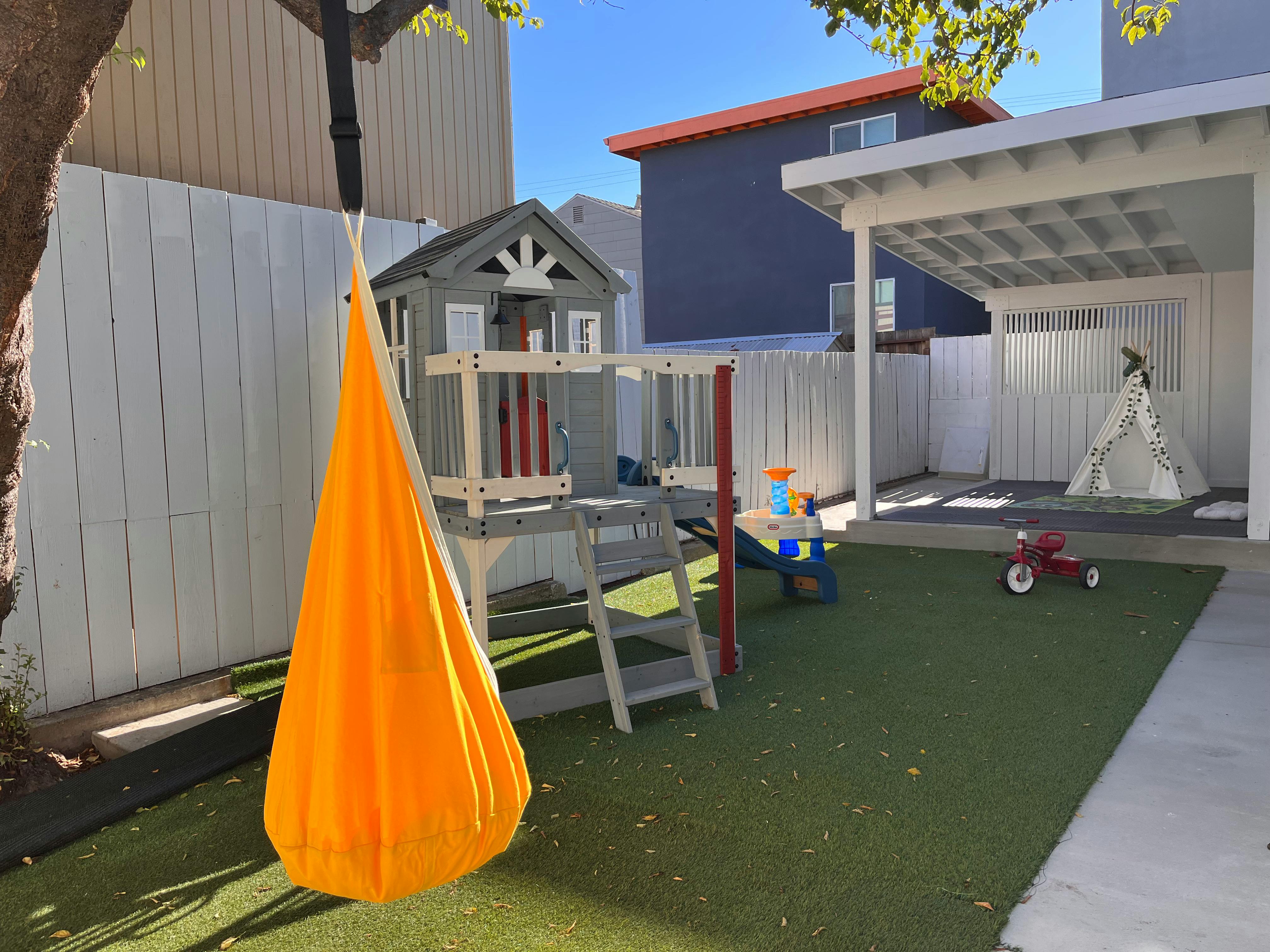 Yellow hanging swing next to a play structure in a backyard