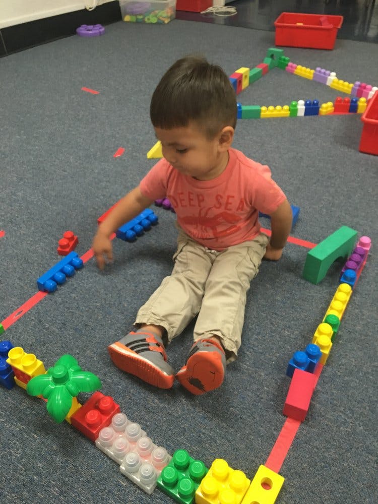 Child sitting on floor playing with colorful building blocks