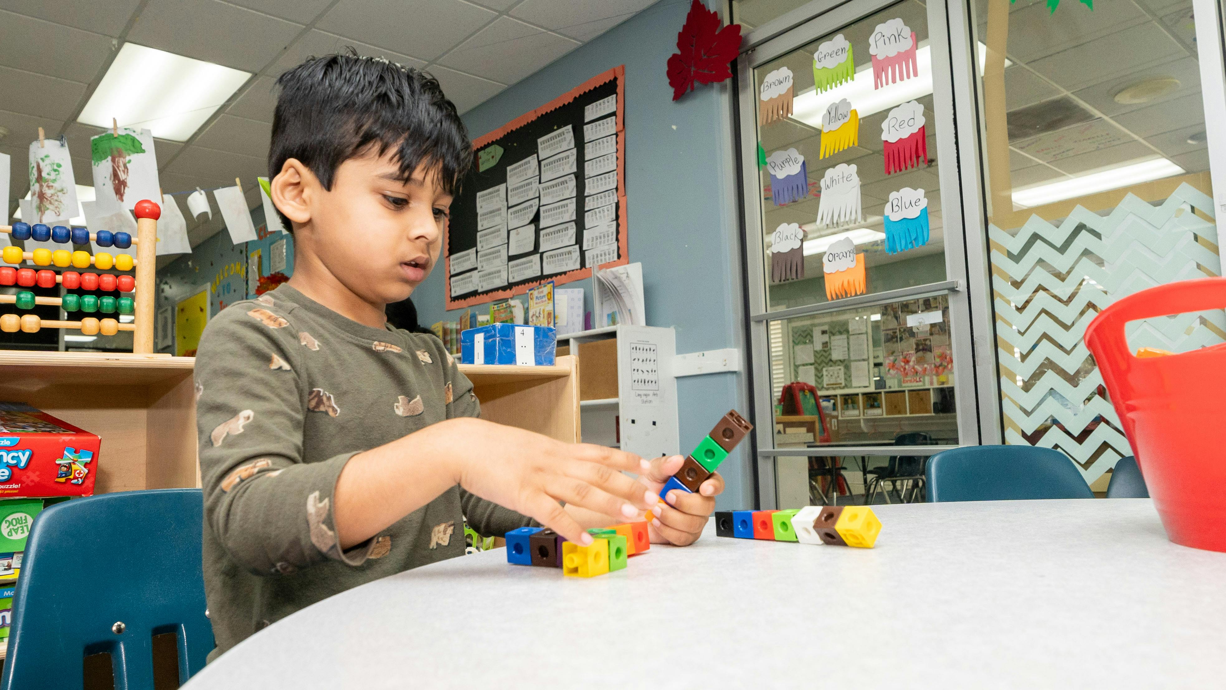 Child playing with colorful building blocks at a table