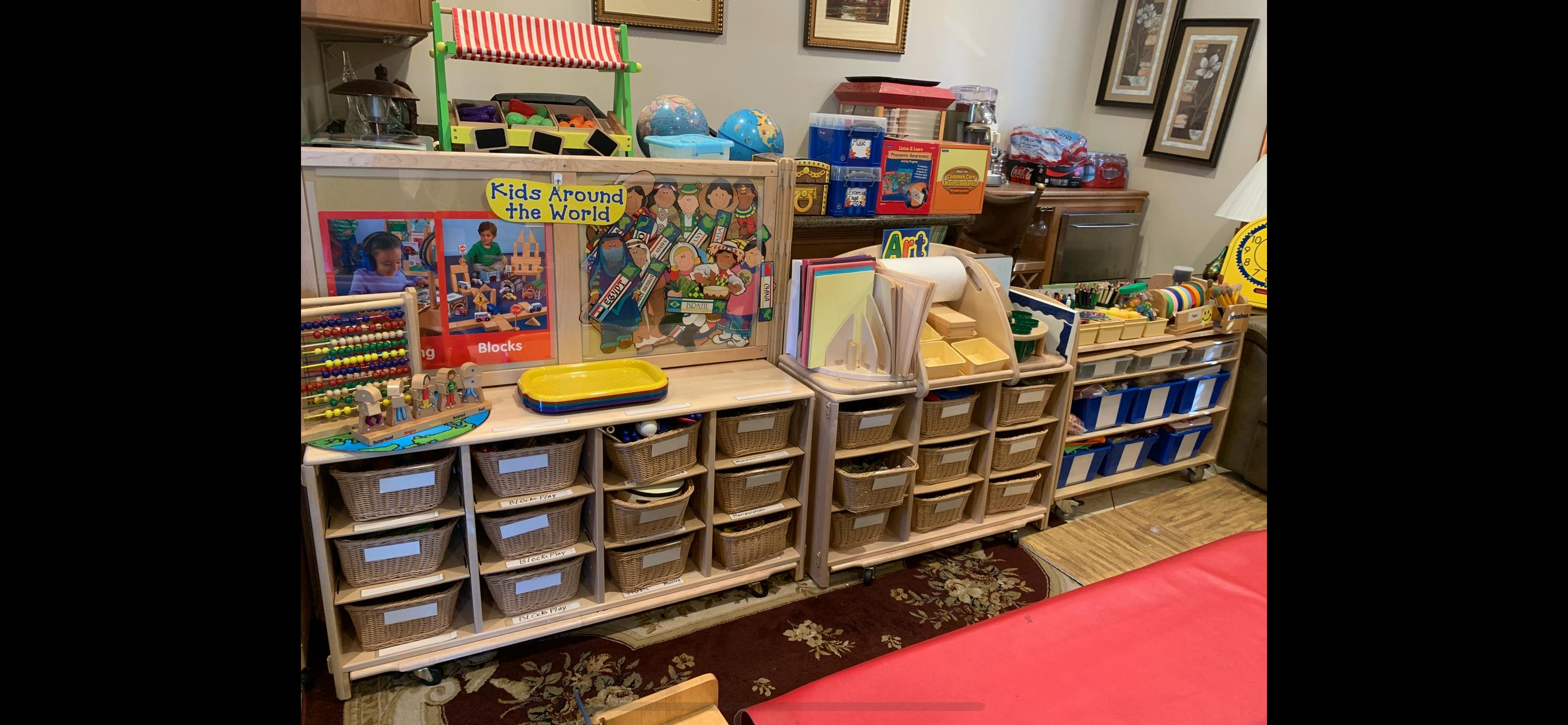 Classroom storage with wicker baskets, teaching materials, and a Kids Around the World poster
