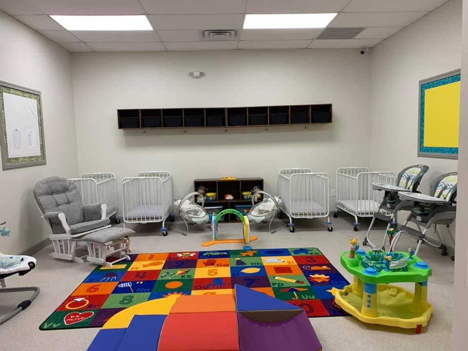 Nursery room with cribs, high chairs, and colorful play mats
