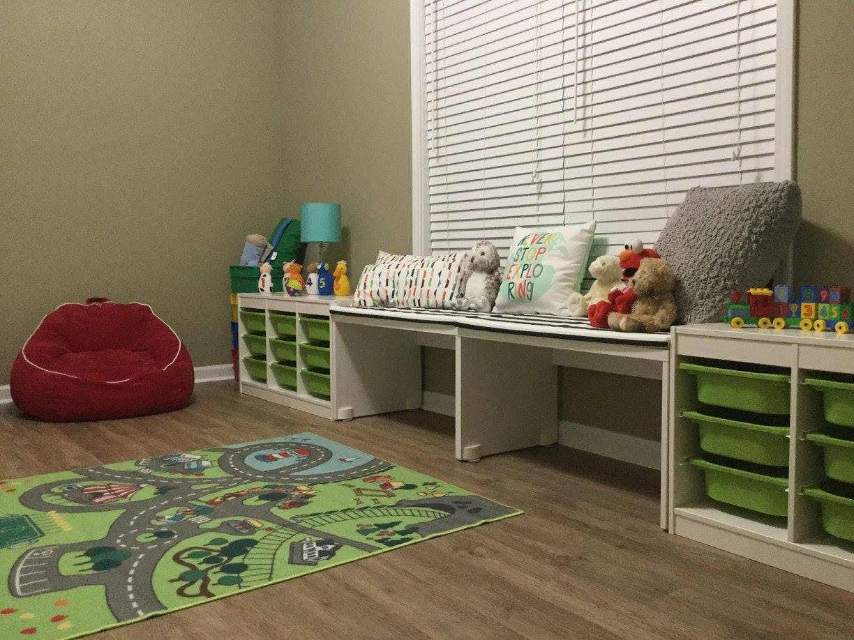 Playroom with a red beanbag chair, storage units, and a road map rug
