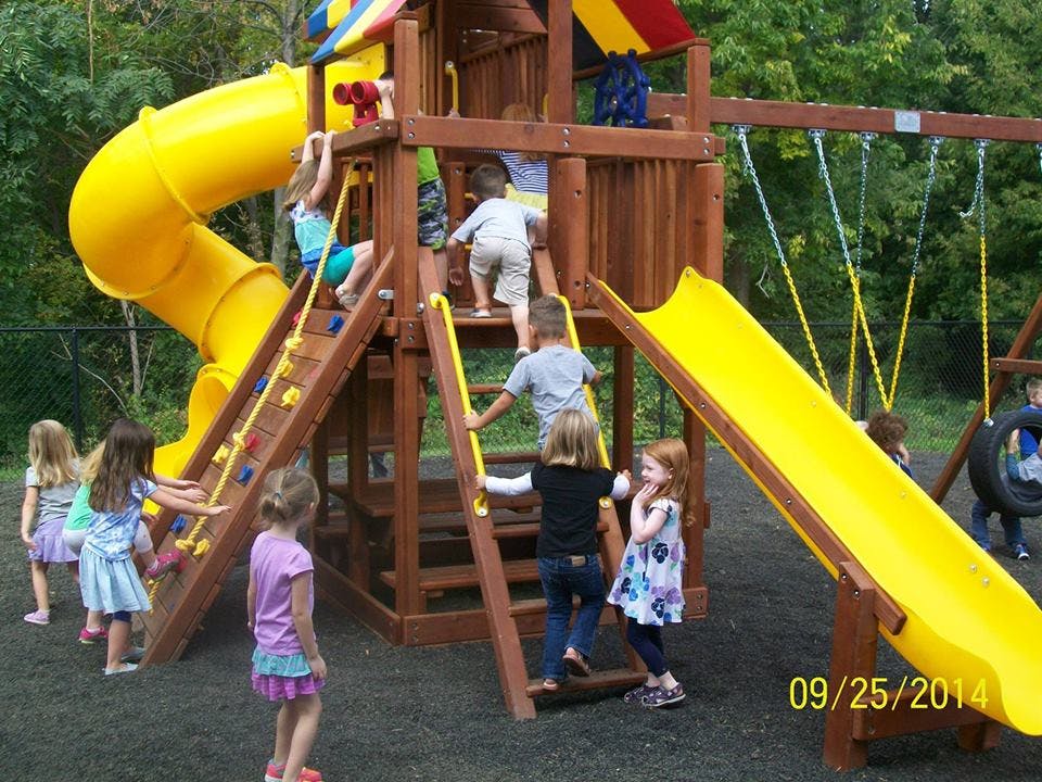 Children playing on a wooden playground structure with yellow slides