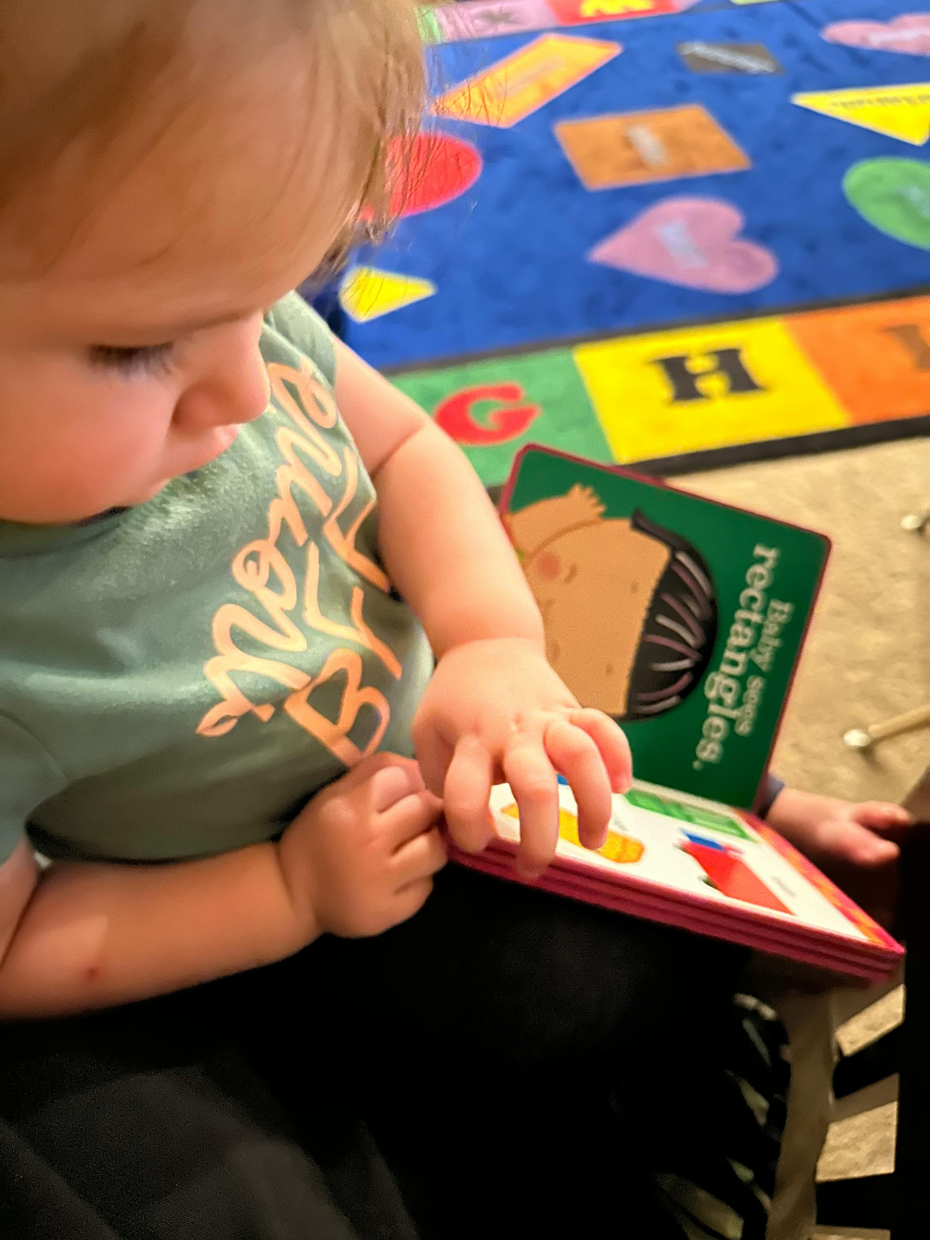 Child looking down at a book with shapes