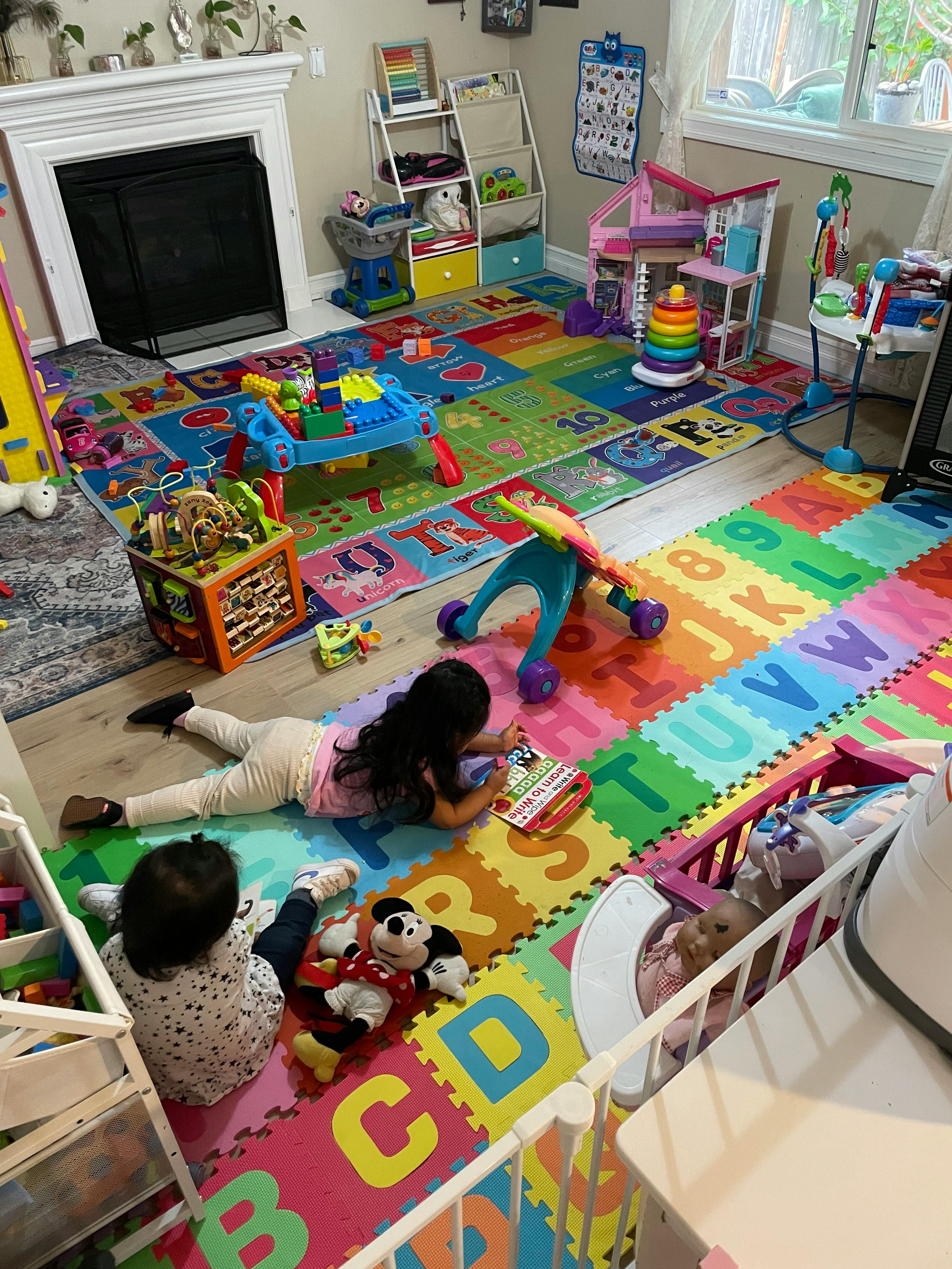 Two children playing on a colorful alphabet mat in a playroom