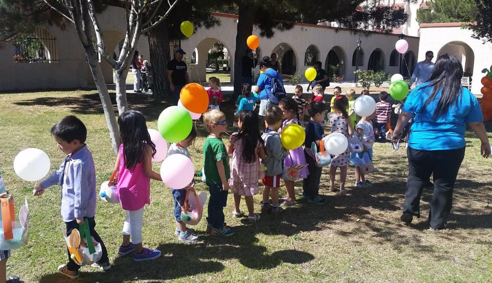 Children holding balloons in a line outdoors