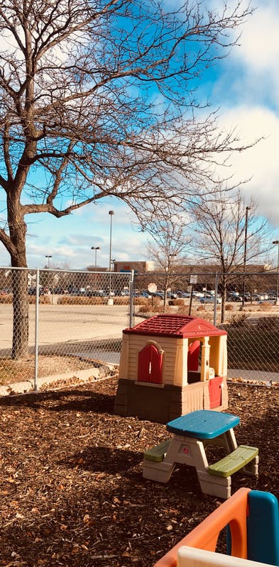 Playhouse and picnic table on wood chips next to a fence