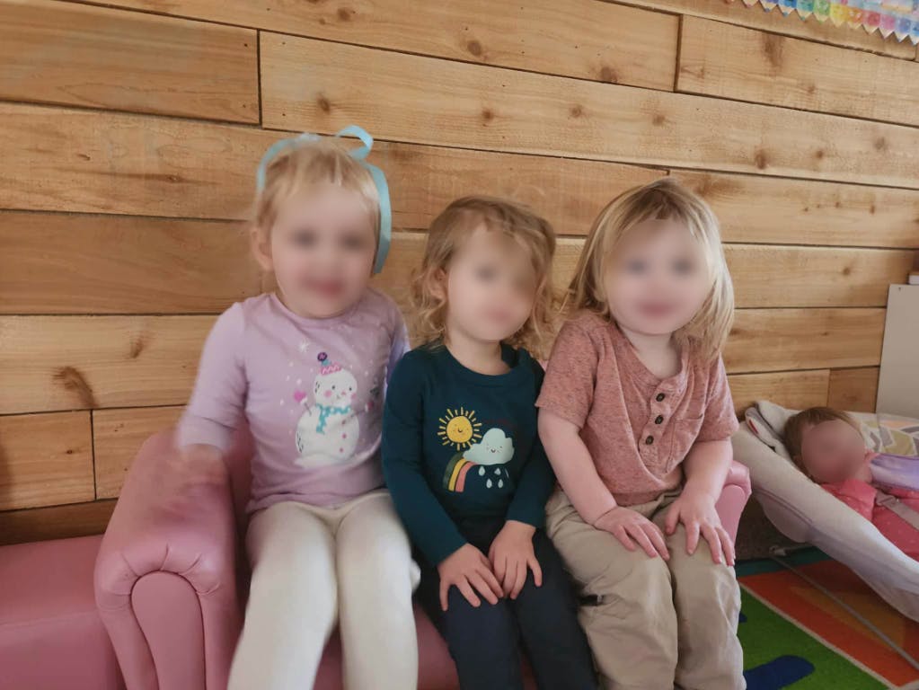 Three children sitting on a pink couch