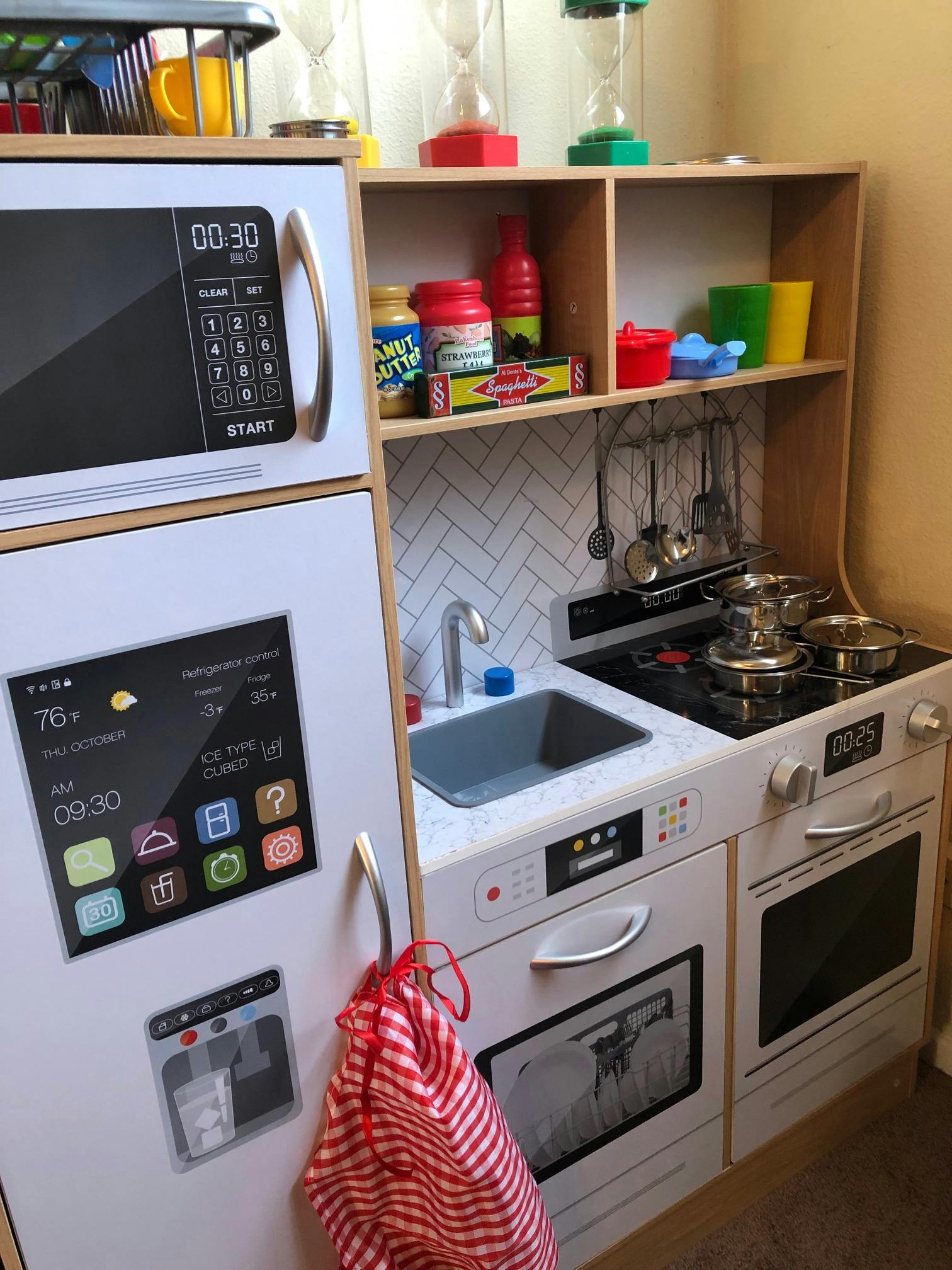 Child's play kitchen with a refrigerator, microwave, sink, and stove