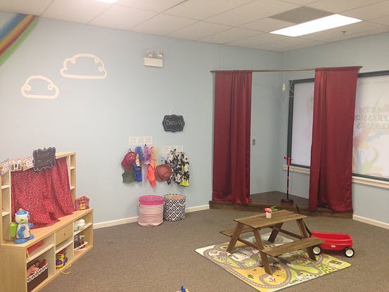 Children's play area with a puppet stage, toy picnic table, and red wagon