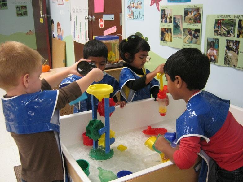 Children playing at a water table in a classroom