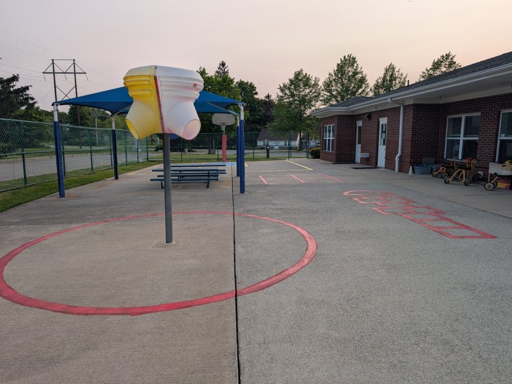Outdoor play area with a colorful structure, covered seating, and a building
