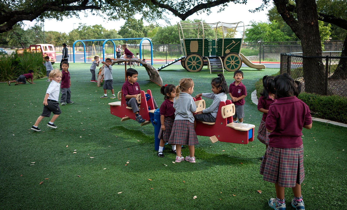Children playing on a playground with a seesaw and other equipment