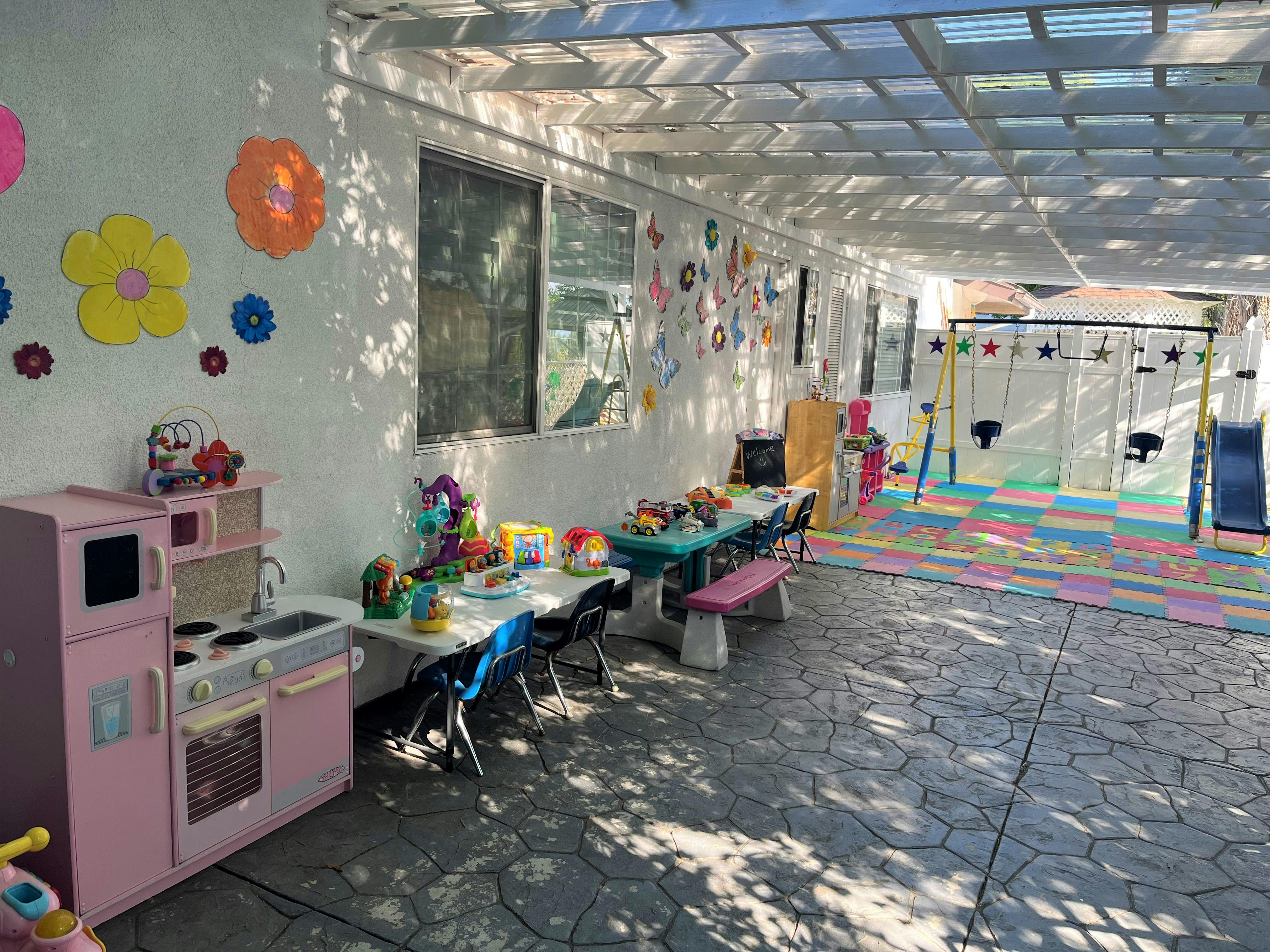 Outdoor play area with tables, chairs, and play kitchen