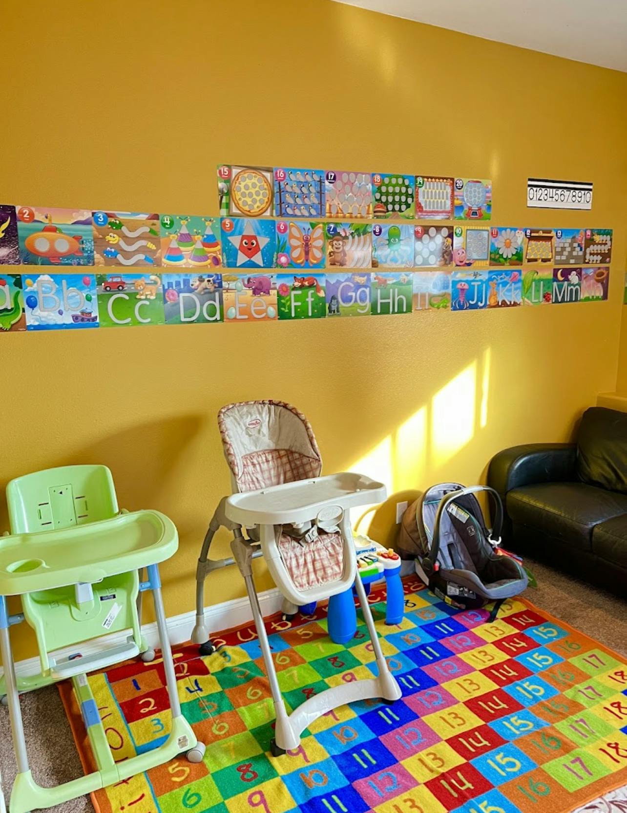 Two high chairs and a car seat on a colorful number rug