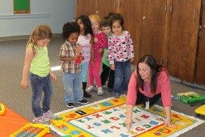 Adult and children playing with alphabet mat
