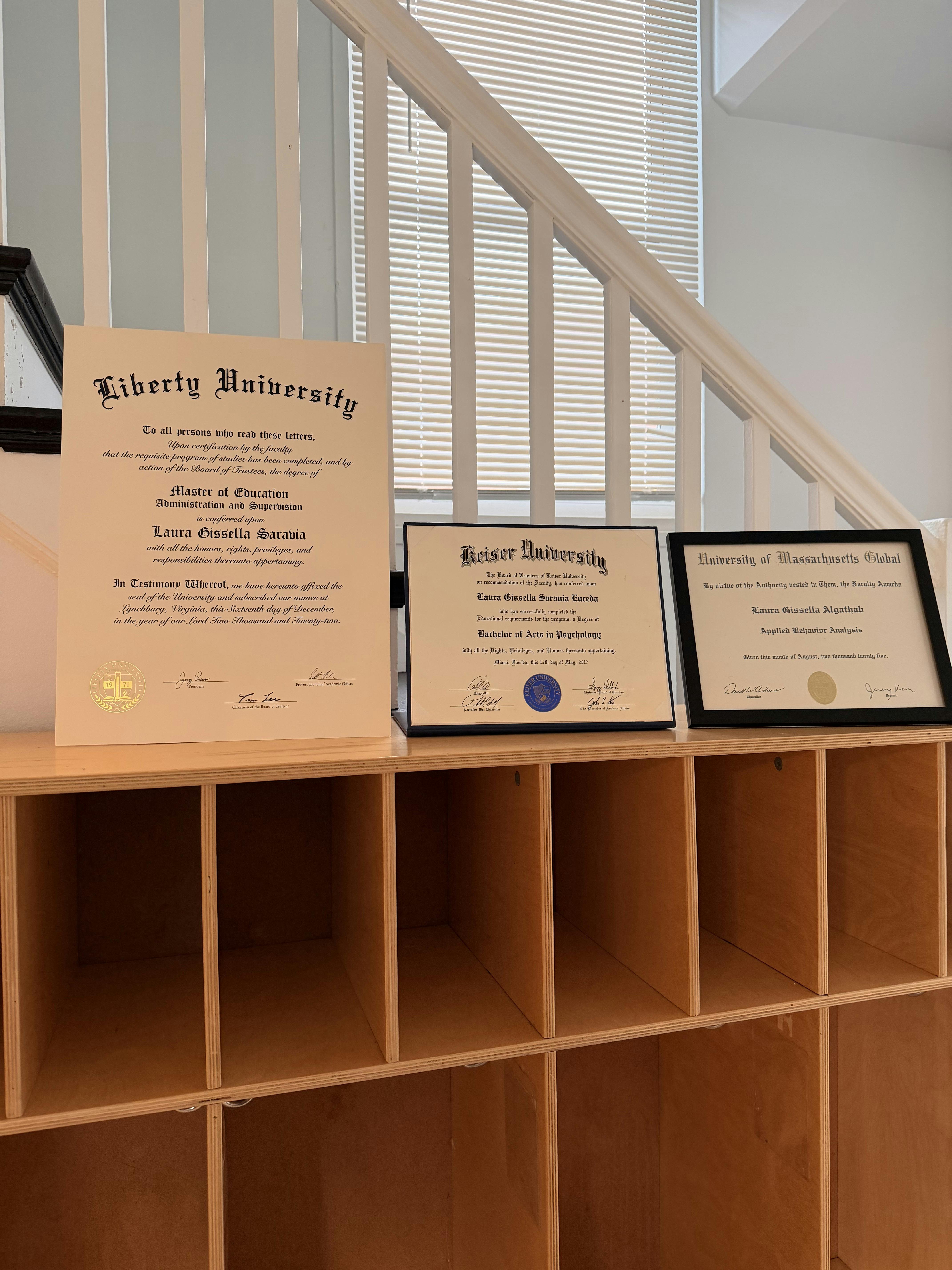 Three university diplomas displayed on a wooden cubby shelf
