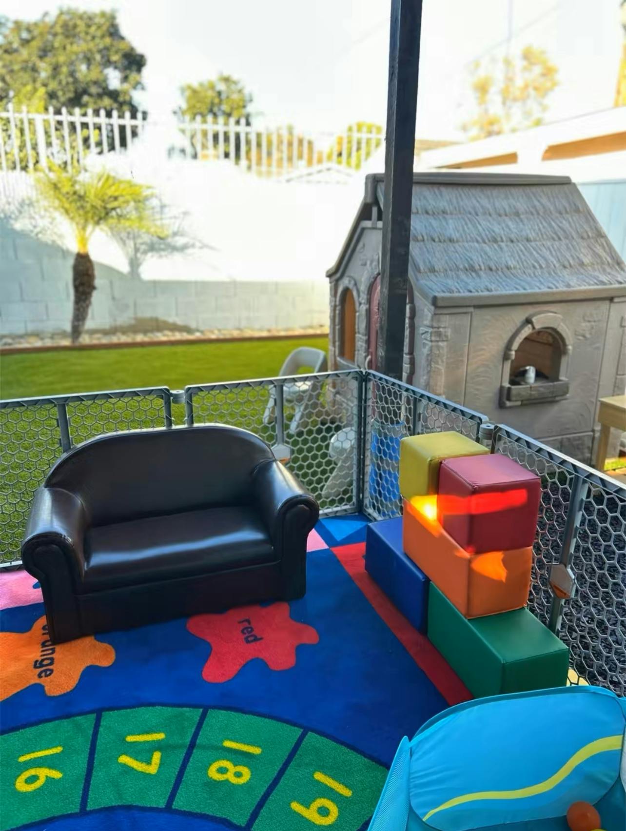 Play area with a child-sized sofa, soft block steps, and a playhouse