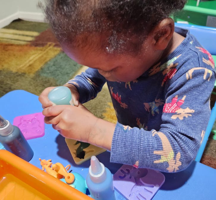 Child squeezing a bottle into a silicone mold