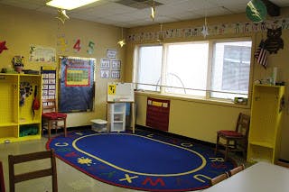 Empty classroom with blue oval rug and windows