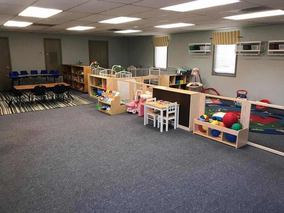 Playroom with small tables, chairs, cribs, and toys