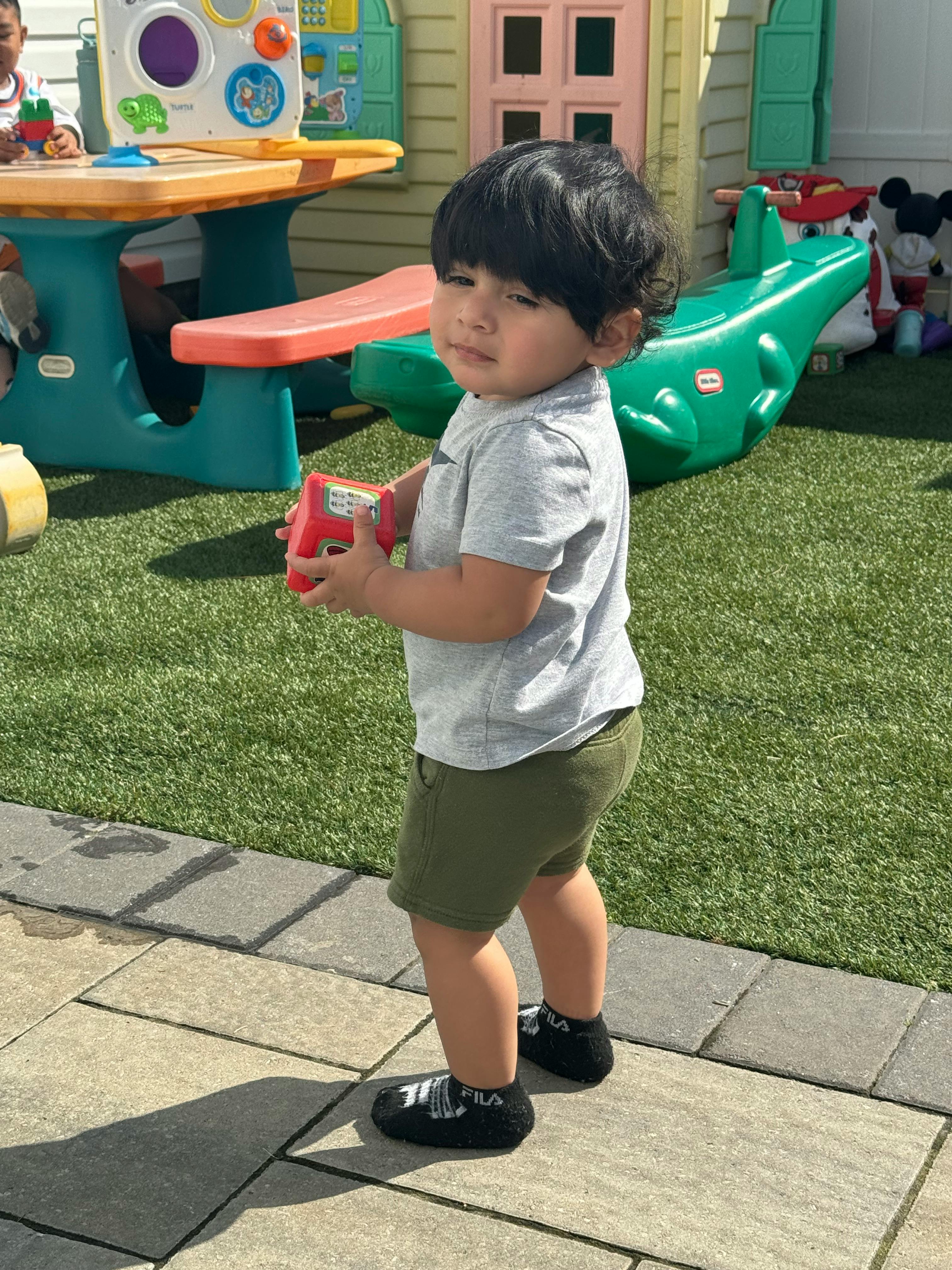 Child holding a red toy in a play area