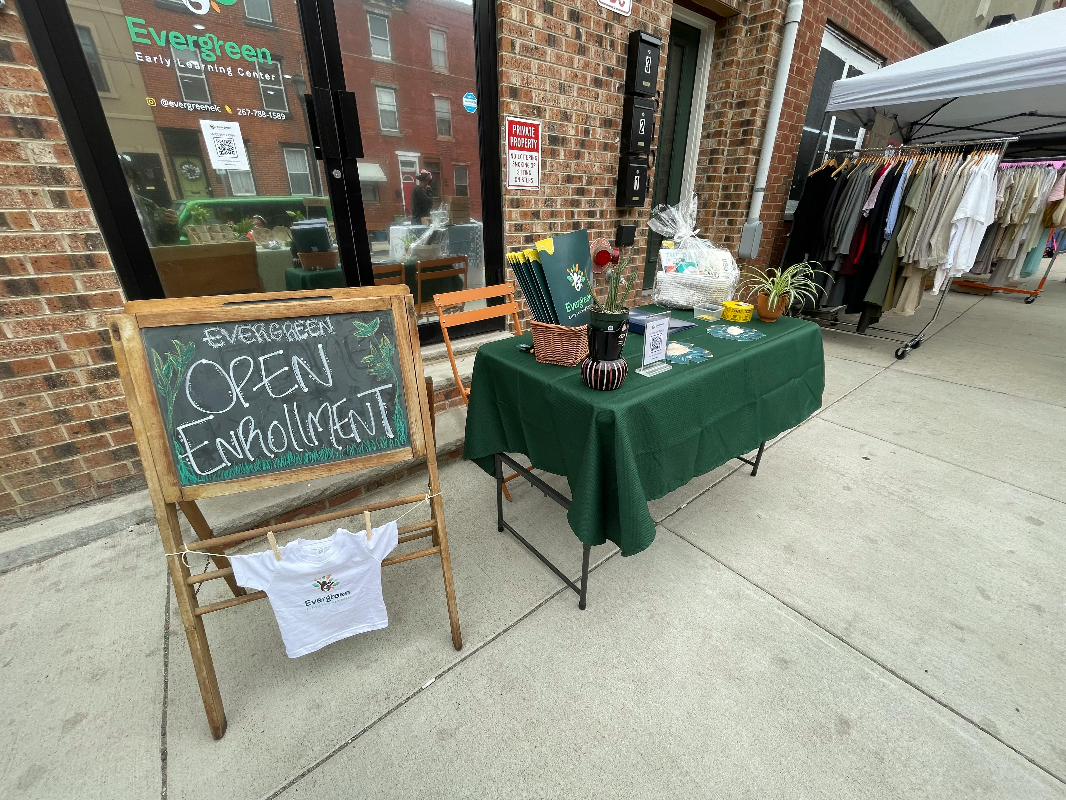 Chalkboard sign with "Open Enrollment" and a table with a green tablecloth