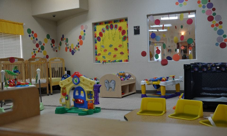 Playroom with cribs, toys, and colorful wall decorations
