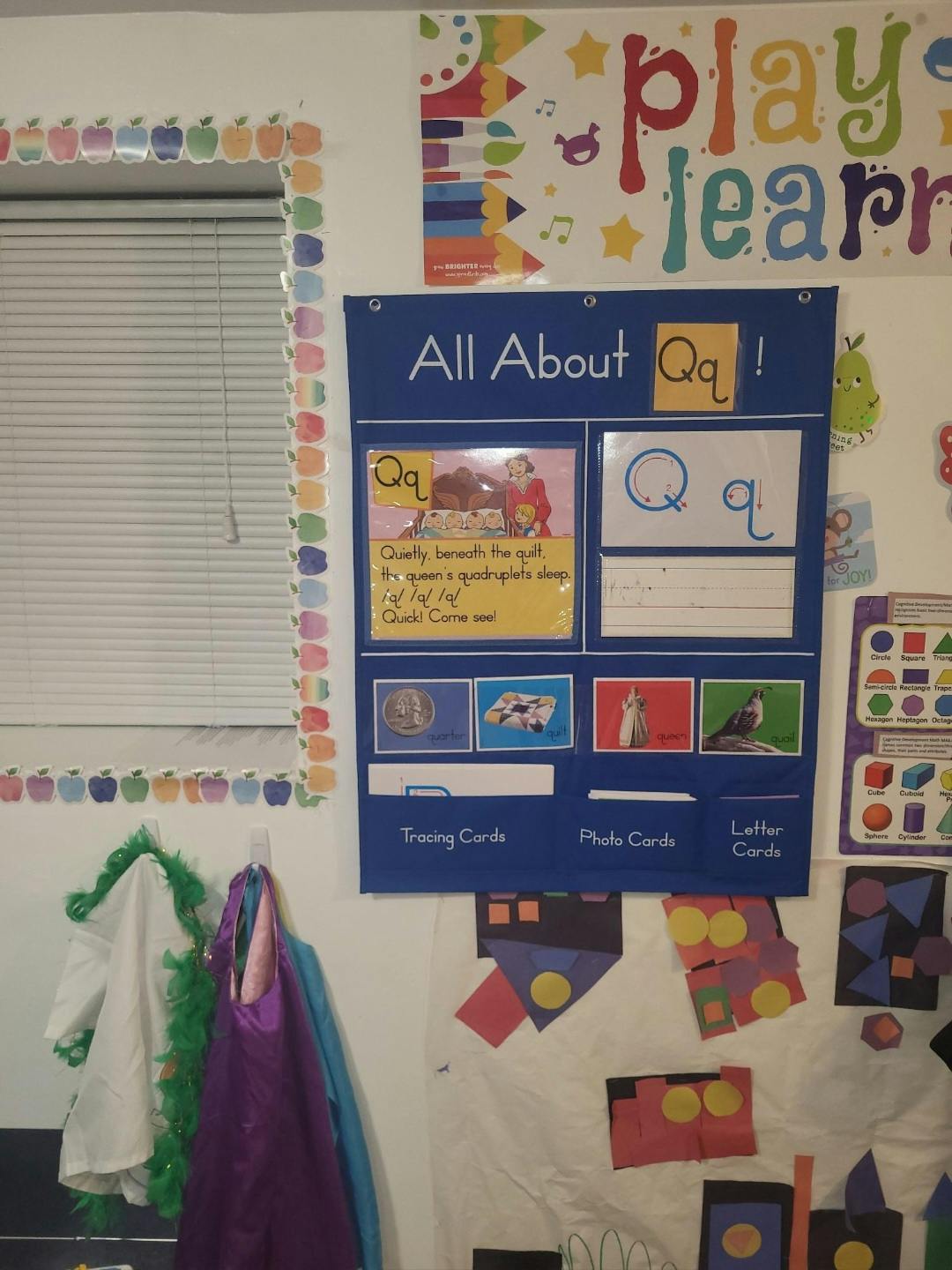 Classroom wall with a "Play Learn" poster and an "All About Qq!" display