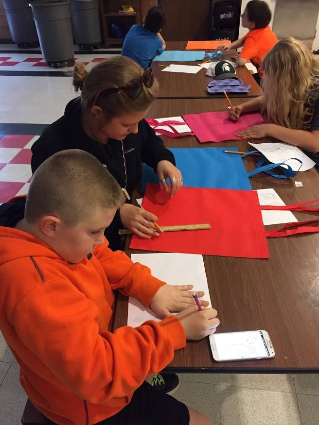 People and children sitting at tables, working on crafts