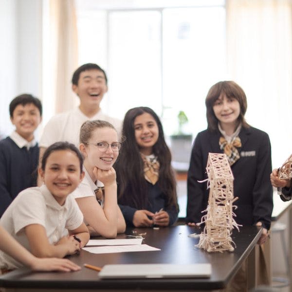 Children in a classroom with a stick tower on a table