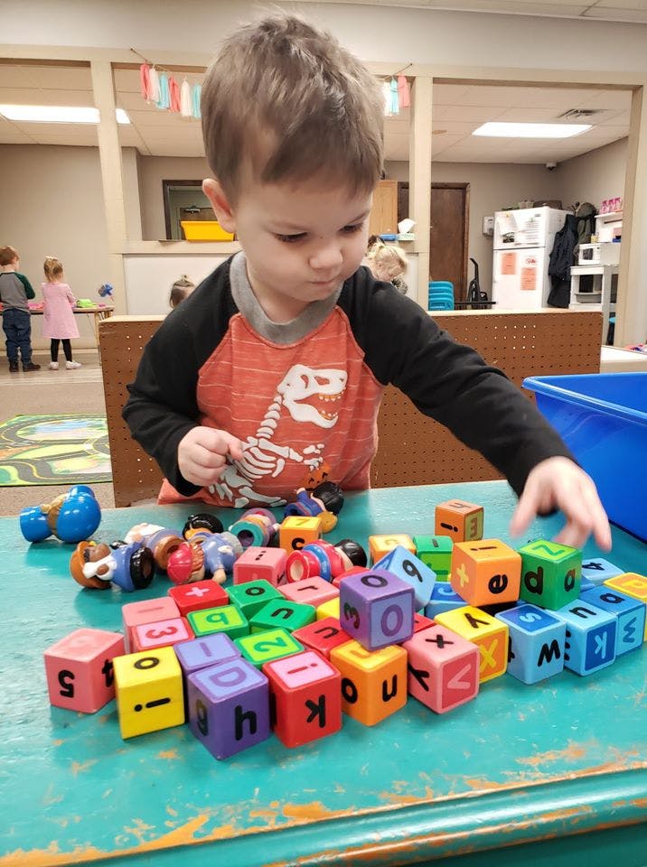 Child playing with alphabet blocks on a table