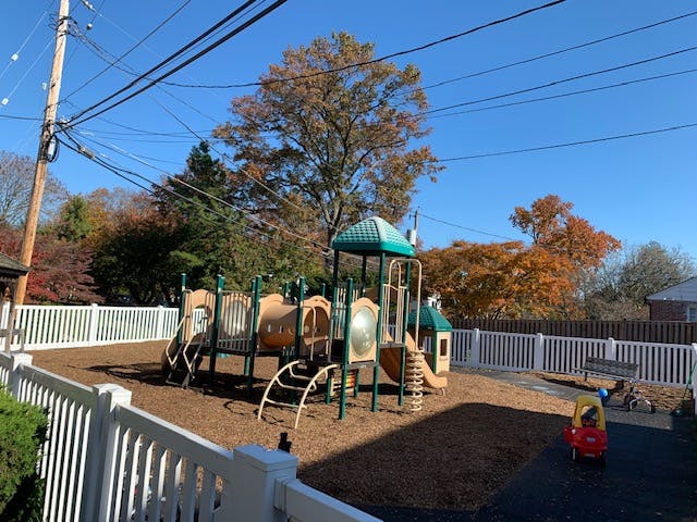 Playground with slides and climbing structures surrounded by a white fence