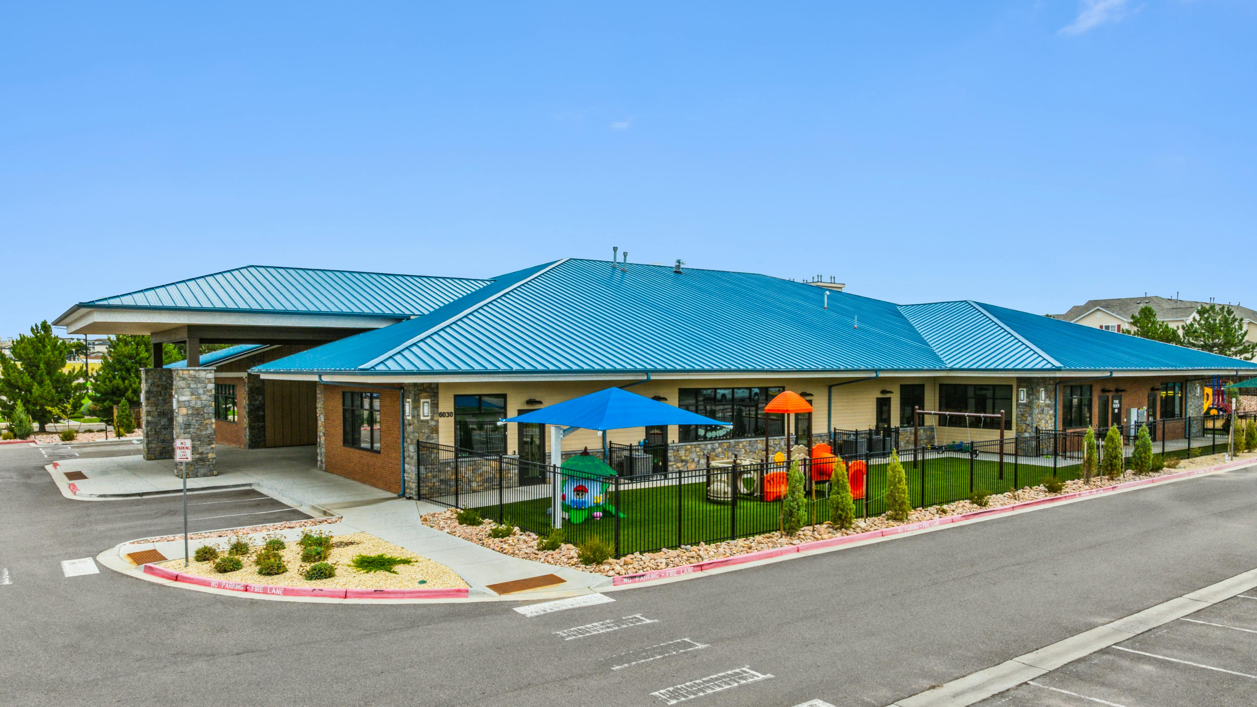 Building with blue roof and an outdoor playground area