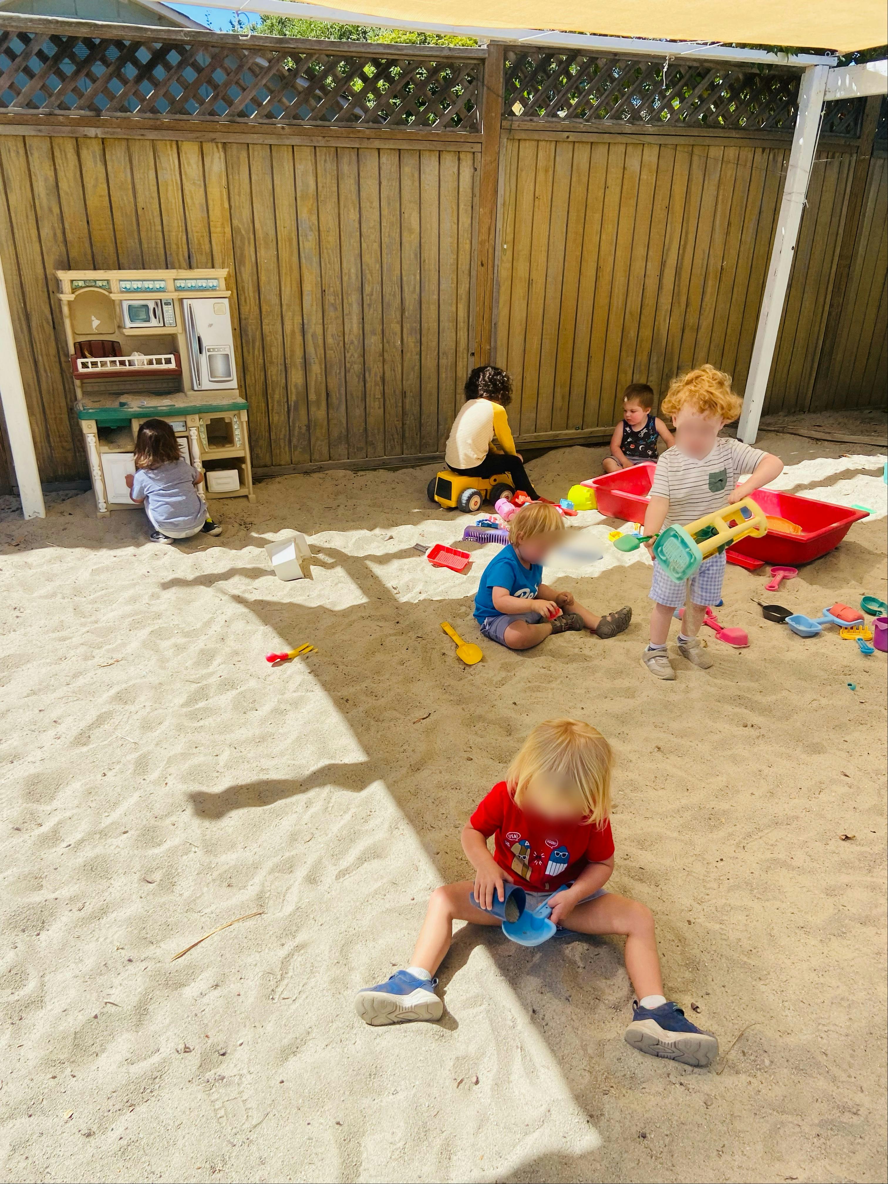 Children playing in a sandbox with toys