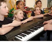 Children gathered around a keyboard
